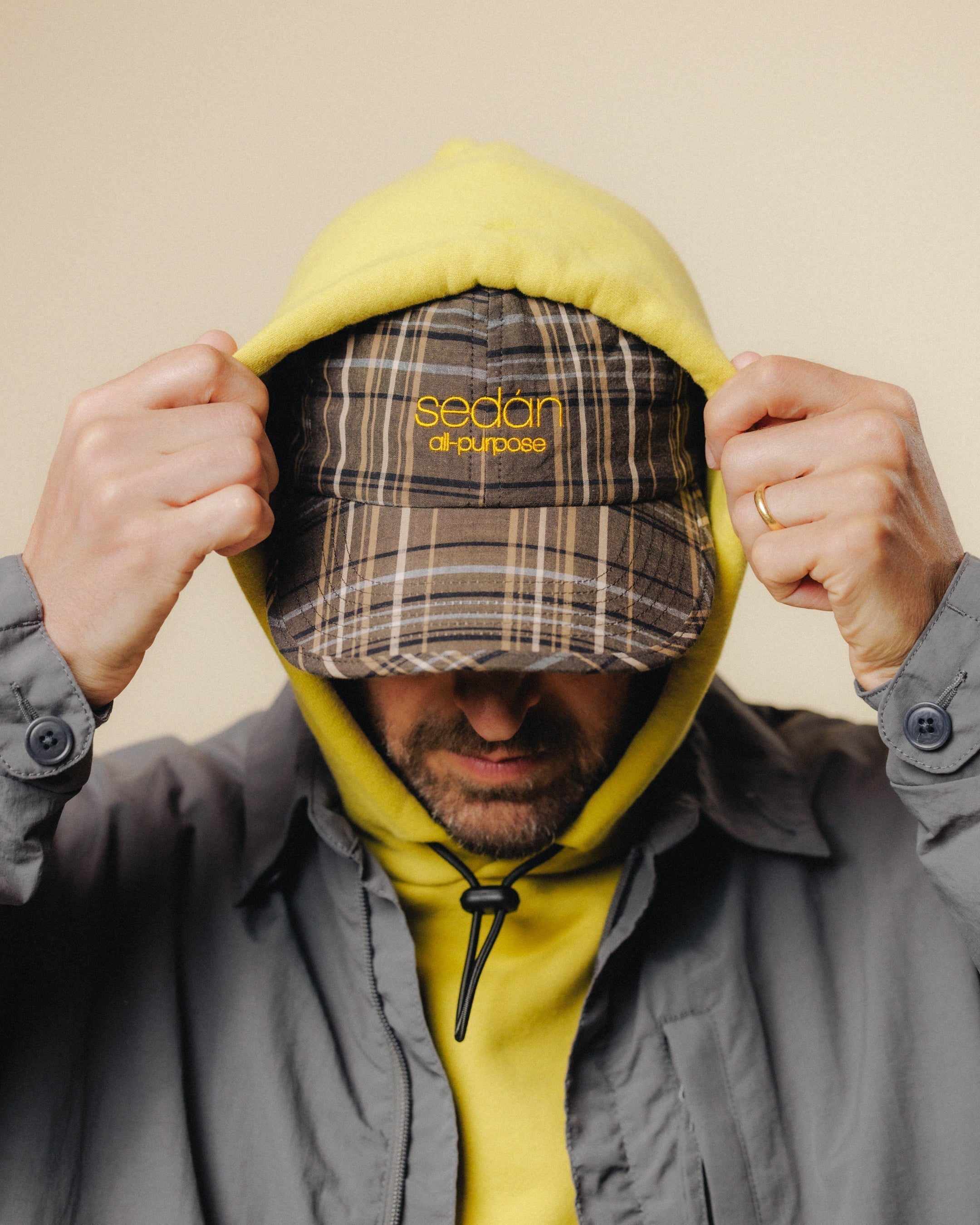 Man wearing "Sedan all Purpose" Cap pulling hoodie up