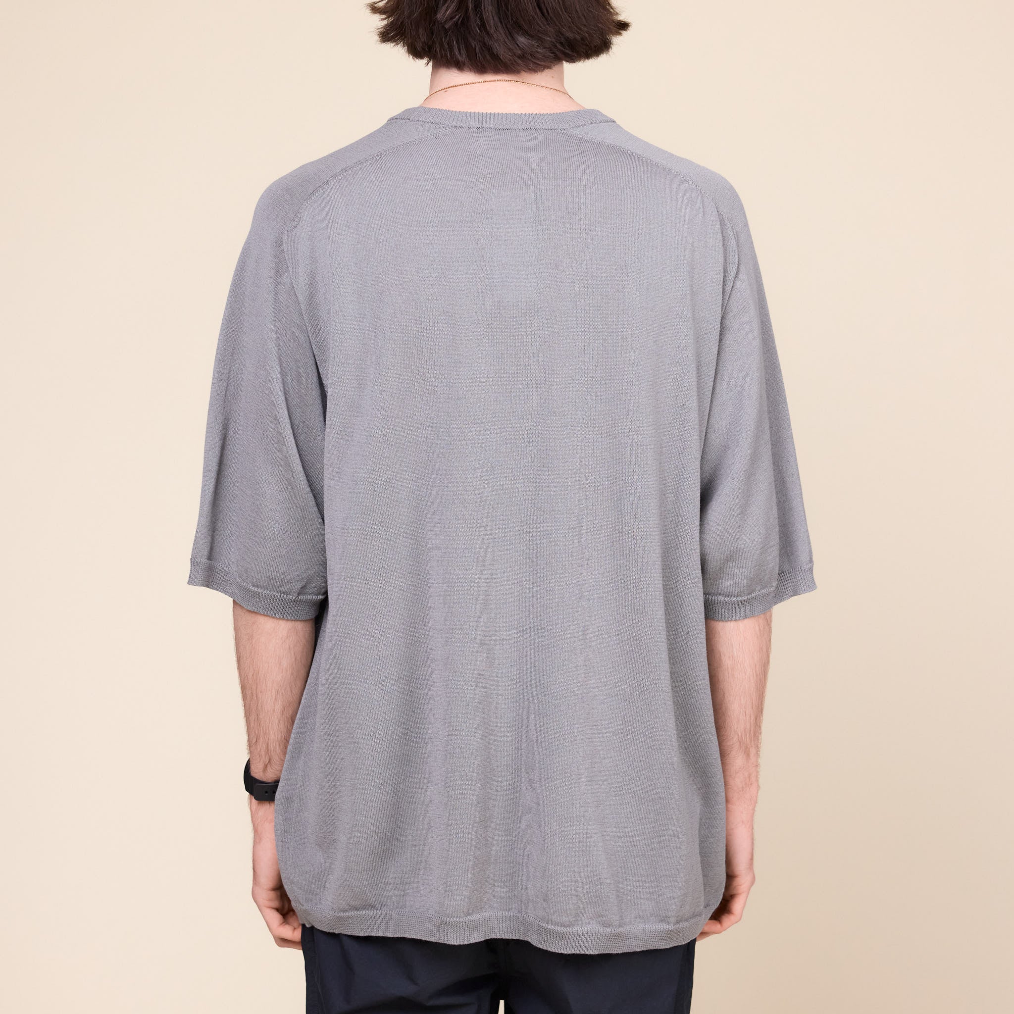 a man wearing a grey Still by Hand 1/2 Sleeve Knit T-Shirt standing against a cream background