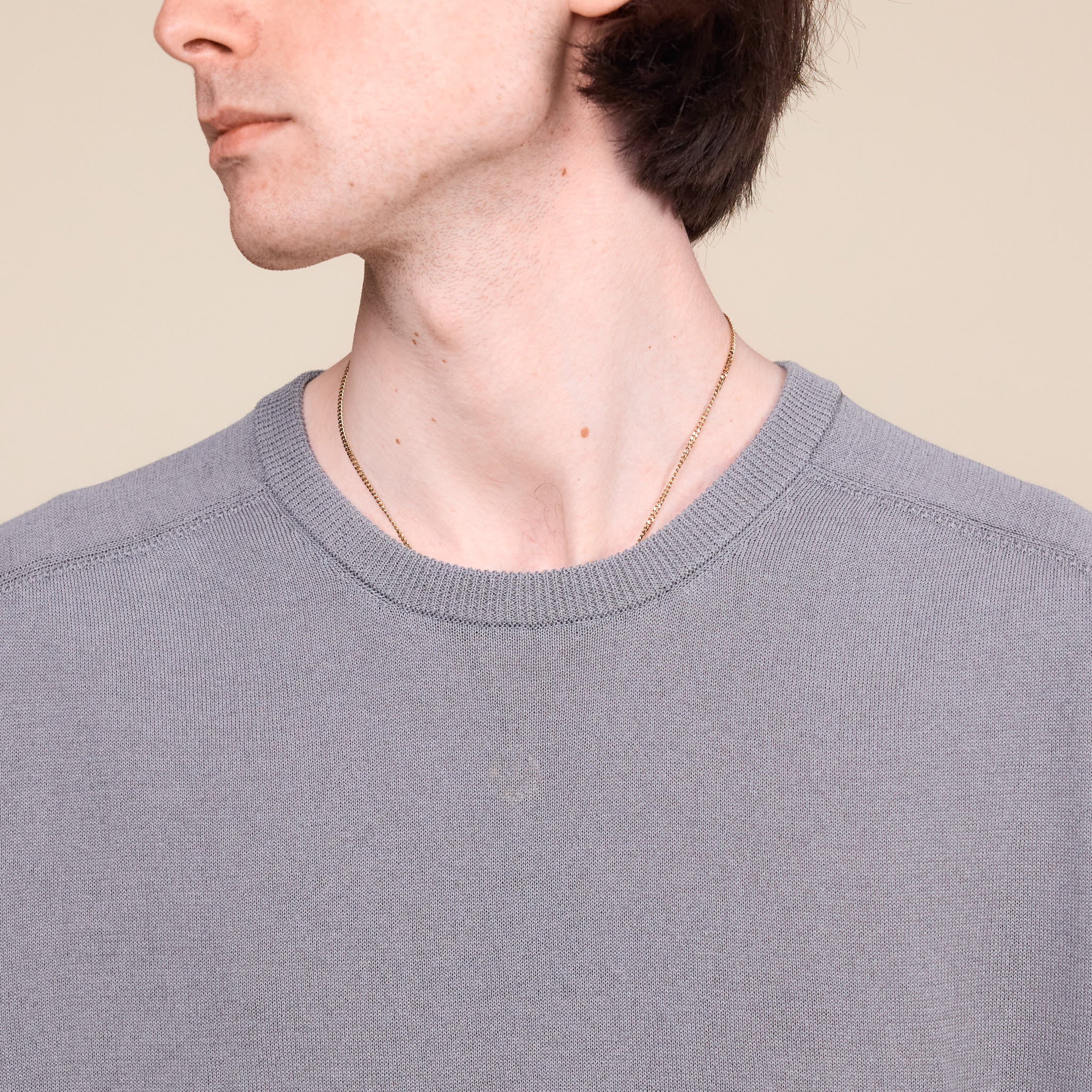 a man wearing a grey Still by Hand 1/2 Sleeve Knit T-Shirt standing against a cream background